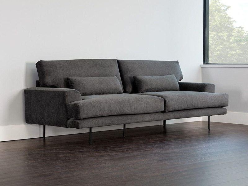 Sofa băng bọc vải màu xám đậm, chụp góc nghiêng từ phía trước, thể hiện kiểu dáng hiện đại với đường nét thanh thoát. Sofa…