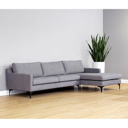 Sofa lệch góc bọc vải cao cấp màu xám đậm, thiết kế thanh mảnh và hiện đại. Sản phẩm nổi bật trên nền tường xám nhạt và sà…