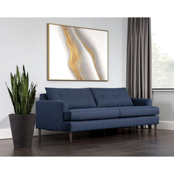 Sofa băng bọc vải màu xanh đậm đặt trong không gian phòng khách tối giản, hiện đại. Góc chụp chéo cho thấy sofa với thiết…