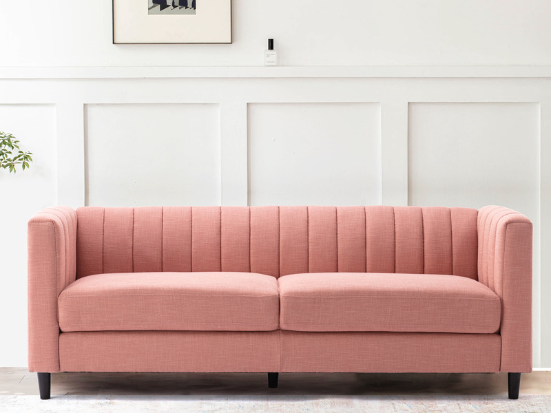 Sofa băng bọc vải màu hồng nhạt, kiểu dáng hiện đại với tựa lưng và tay vịn cao có các đường may dọc tinh tế. Ghế có hai đ…