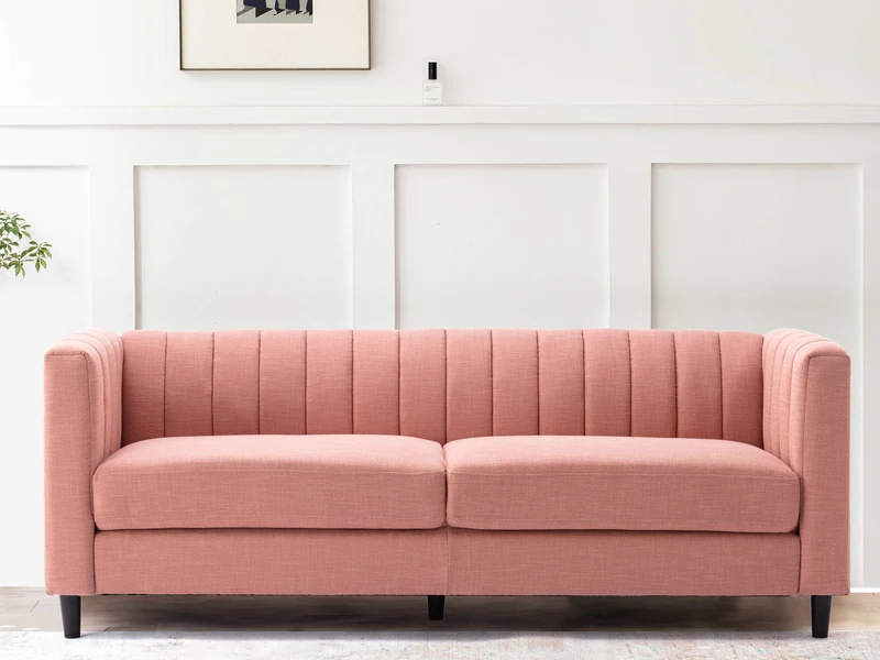 Sofa băng bọc vải màu hồng nhạt, kiểu dáng hiện đại với tựa lưng và tay vịn cao có các đường may dọc tinh tế. Ghế có hai đ…