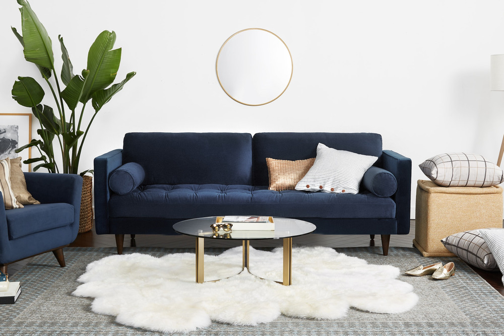 Sofa băng 3 chỗ bọc vải màu xanh cobalt đậm, đặt trong không gian phòng khách hiện đại với tường trắng, sàn gỗ và thảm lôn…