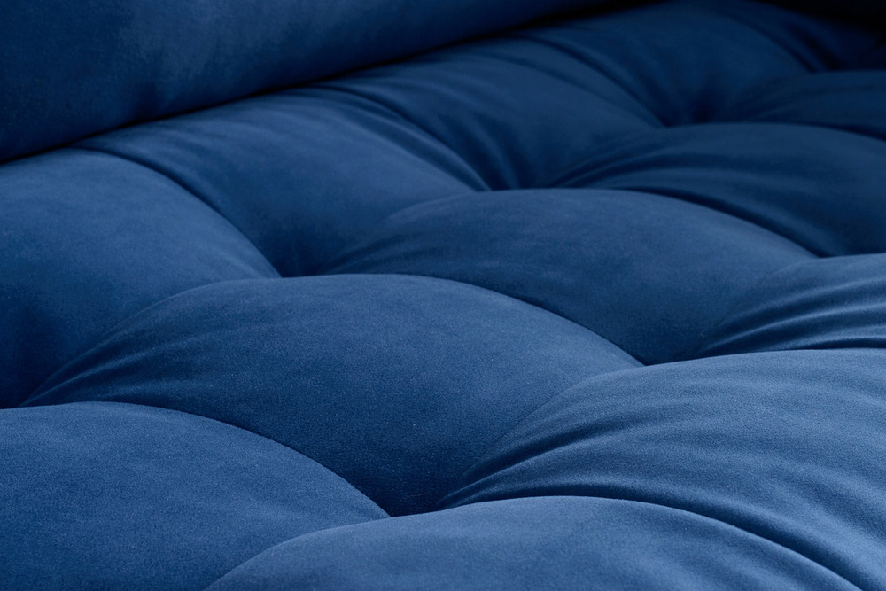 Cận cảnh bề mặt đệm ngồi của sofa bọc vải màu xanh navy, với các đường may tạo múi phồng nhẹ. Chất liệu vải mềm mại, mang…