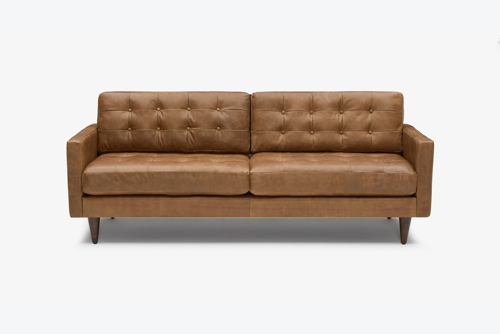 Sofa băng bọc da công nghiệp cao cấp màu nâu caramel, chụp chính diện trên nền trắng. Thiết kế nổi bật với các nút rút múi…