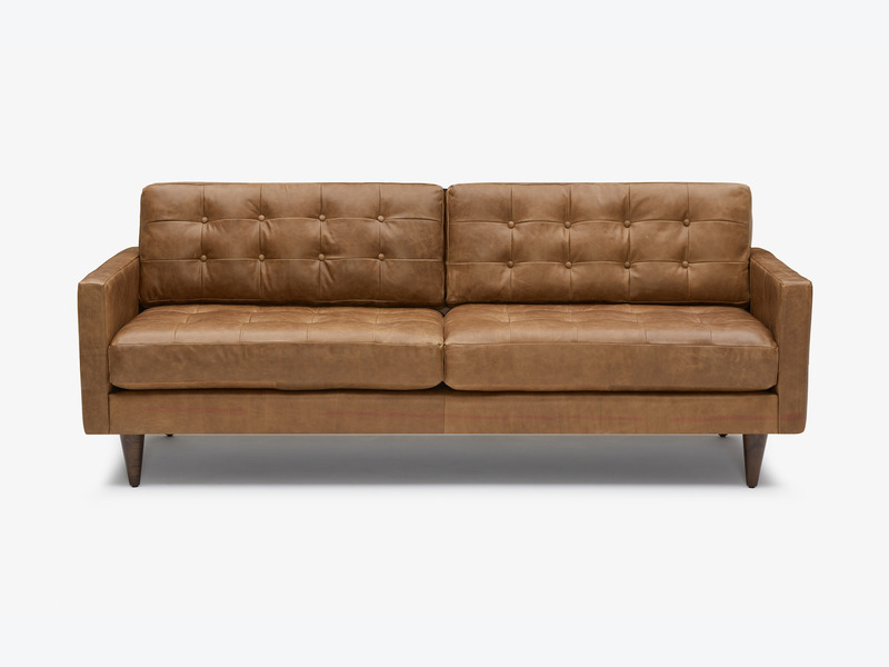 Sofa băng bọc da công nghiệp cao cấp màu nâu caramel, chụp chính diện trên nền trắng. Thiết kế nổi bật với các nút rút múi…