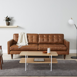 Sofa băng bọc da màu nâu caramel, phong cách mid-century, đặt trong phòng khách hiện đại. Sofa có thiết kế tối giản với ch…