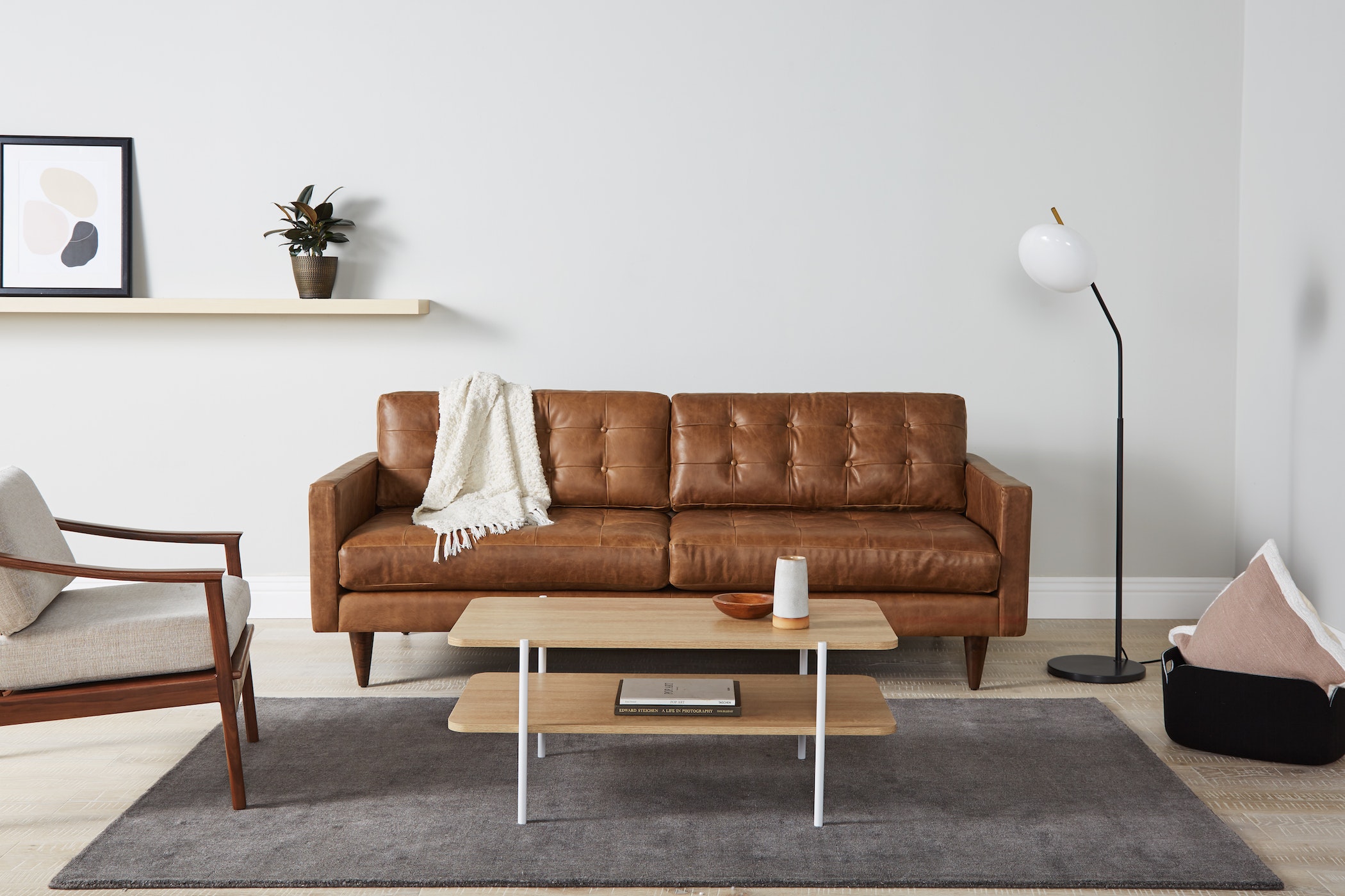 Sofa băng bọc da màu nâu caramel, phong cách mid-century, đặt trong phòng khách hiện đại. Sofa có thiết kế tối giản với ch…