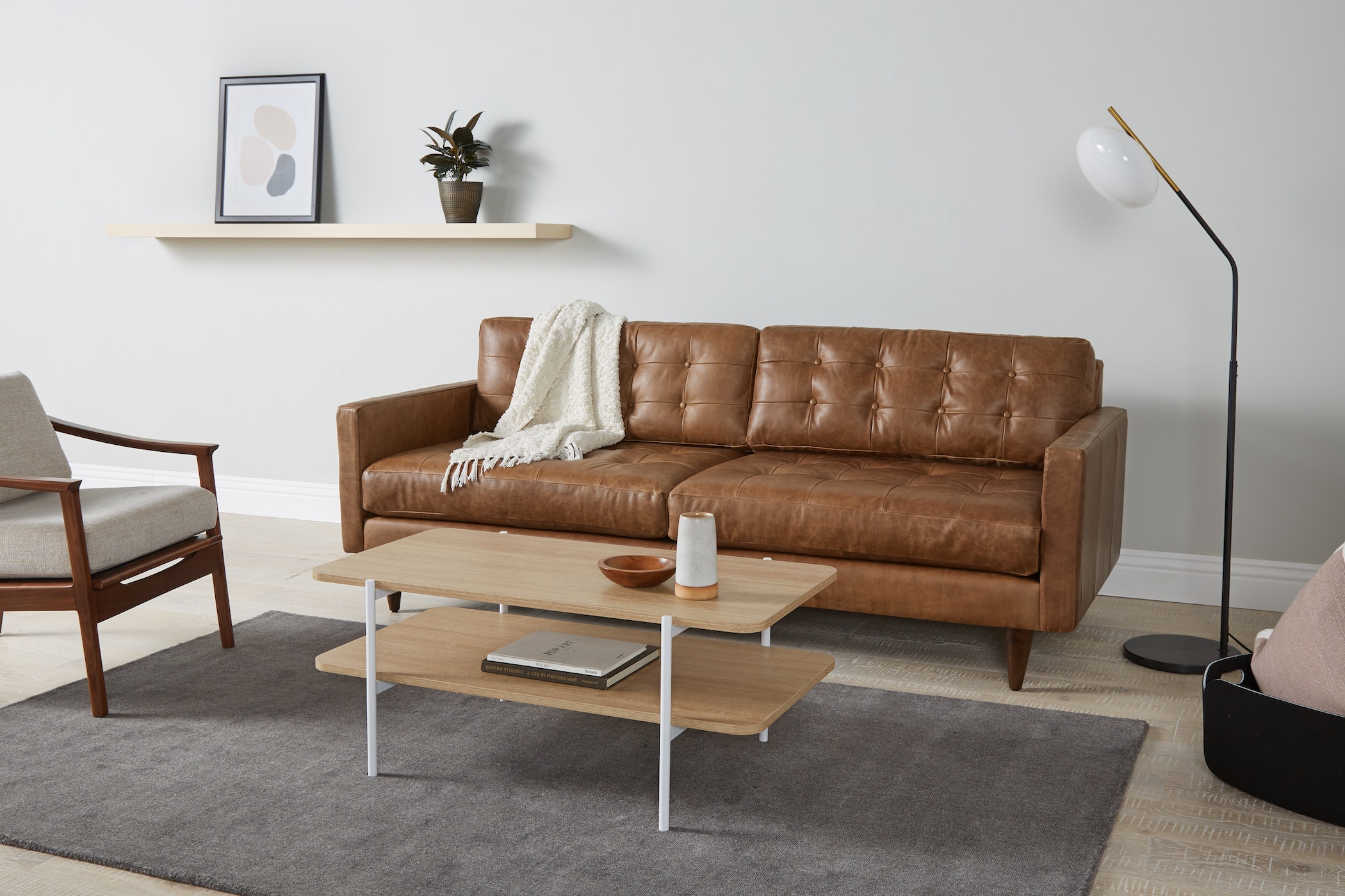 Sofa băng bọc da màu nâu caramel, đặt trong không gian phòng khách hiện đại với ánh sáng tự nhiên. Sofa có thiết kế tối gi…