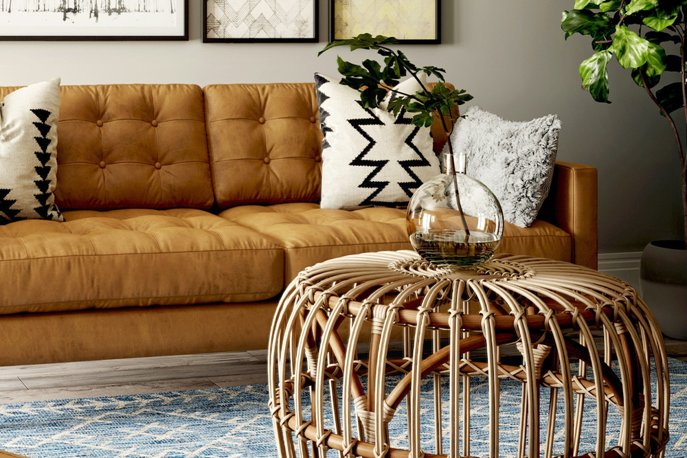 Cận cảnh phần tay vịn và đệm ngồi của sofa bọc da màu nâu caramel, với các gối tựa họa tiết hình học màu trắng đen. Sofa đ…