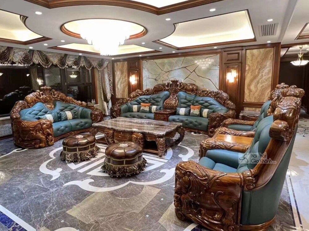 Một bộ sofa gỗ mun khác với thiết kế tương tự, bọc da màu xanh ngọc bích, đặt trong không gian phòng khách luxury với sàn…