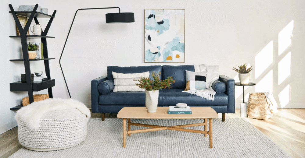 Toàn cảnh phòng khách hiện đại với sofa băng màu xanh navy làm điểm nhấn, kết hợp bàn trà gỗ, thảm lông trắng và đèn sàn k…