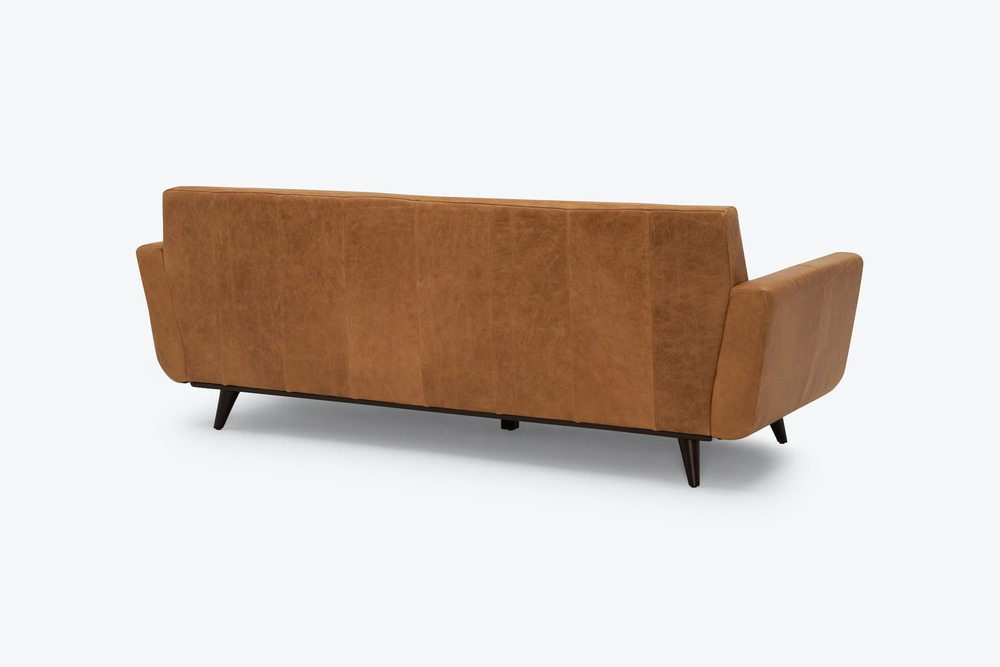 Sofa băng dáng thuyền Hughes SF-555 màu nâu da bò, chụp từ phía sau lưng ghế trên nền trắng. Mặt lưng ghế được thiết kế đơ…