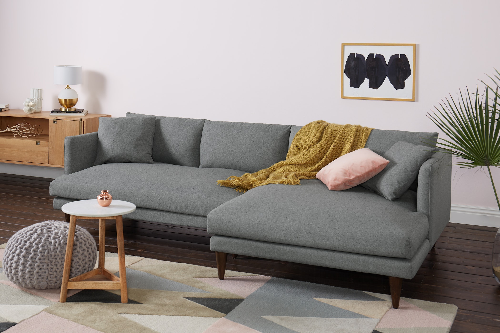 Sofa góc chữ L Lewis SF-489 bọc vải màu xám nhạt, đặt trong phòng khách hiện đại với tường hồng phấn. Sofa thiết kế tối gi…
