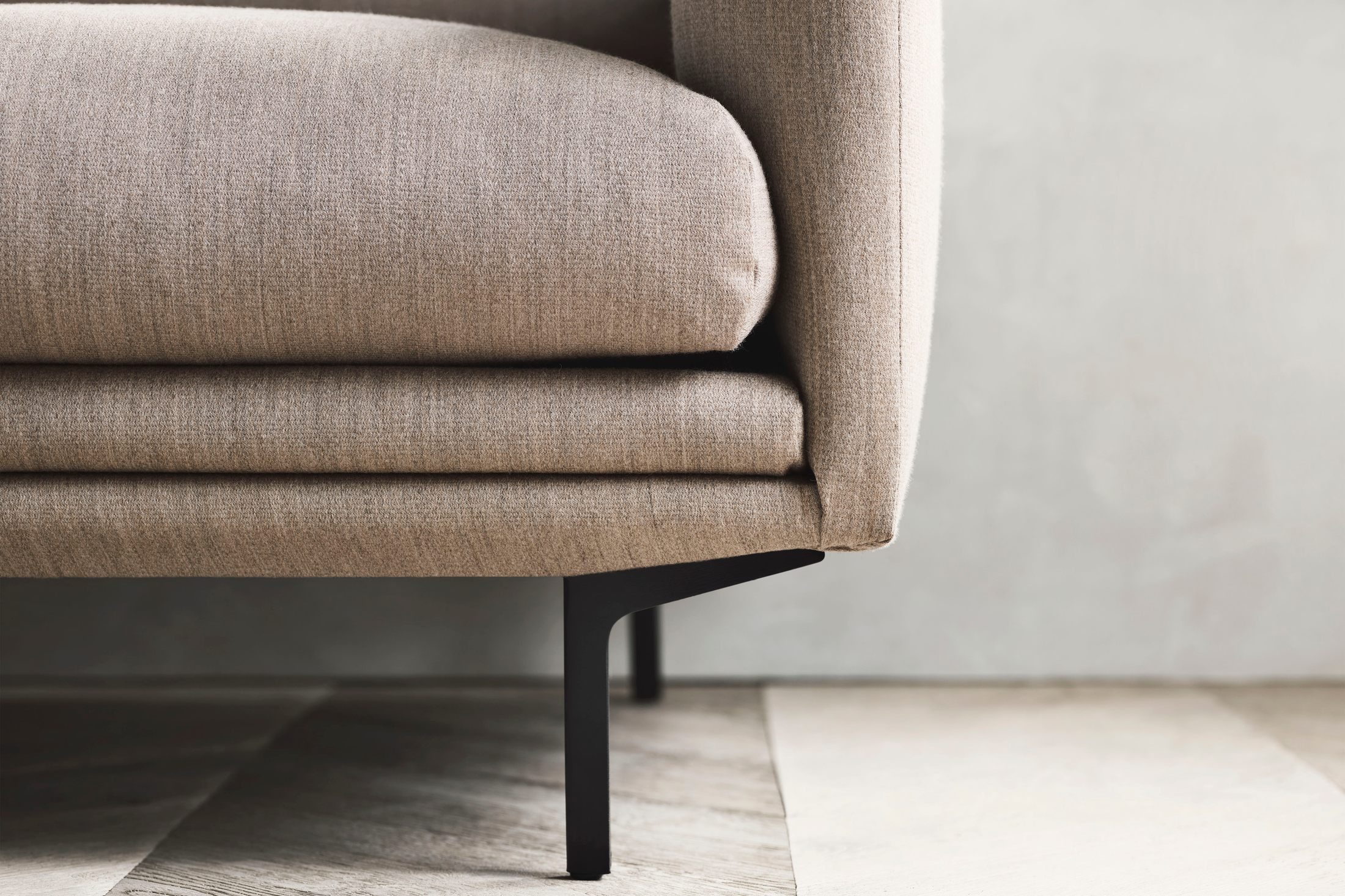 Cận cảnh phần chân sofa làm từ thép không gỉ màu đen, kết nối liền mạch với khung sofa. Phần đệm ngồi bọc vải màu be nhạt…
