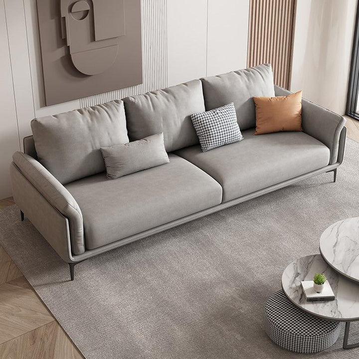 Sofa băng bọc da hiện đại Trudie SF-219 màu xám nhạt, chụp từ góc trên bên phải. Sofa có thiết kế thanh mảnh với chân kim…