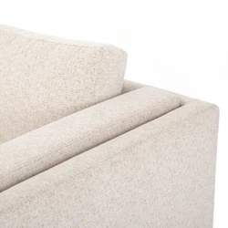 Cận cảnh chi tiết tay vịn và đệm tựa lưng của sofa Ezra SF-222. Bề mặt vải bọc màu be nhạt có kết cấu dệt rõ nét, mang lại…