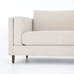 Cận cảnh phần tay vịn và đệm ngồi của sofa Ezra SF-222, cùng với chân ghế côn nhẹ màu nâu sẫm. Chi tiết đường may tinh tế…