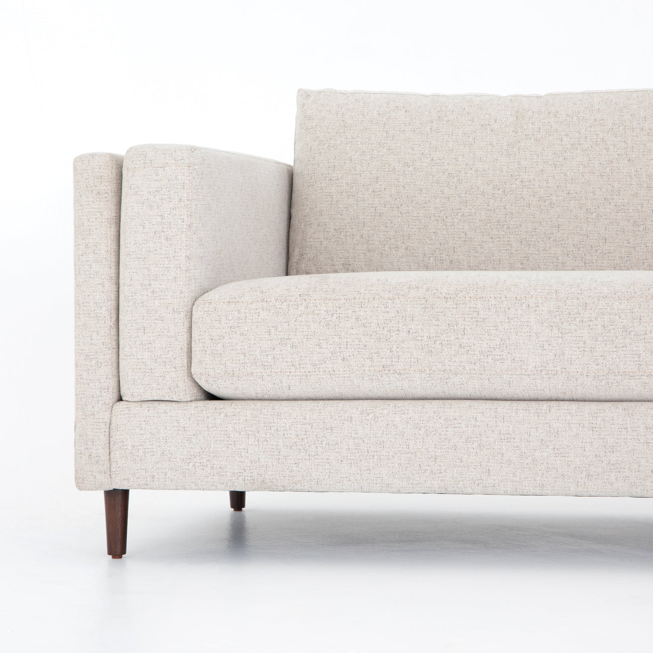 Cận cảnh phần tay vịn và đệm ngồi của sofa Ezra SF-222, cùng với chân ghế côn nhẹ màu nâu sẫm. Chi tiết đường may tinh tế…