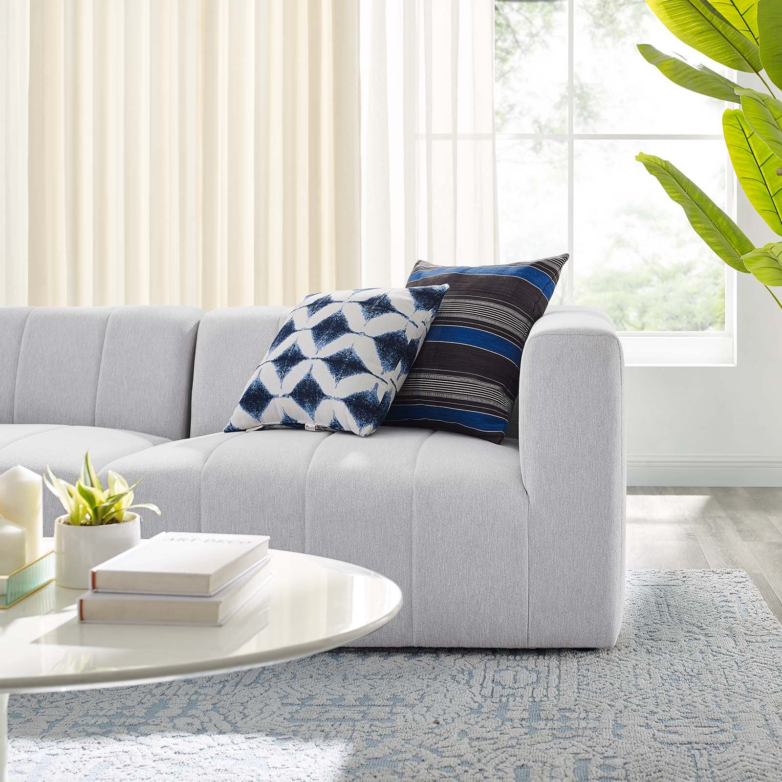 Cận cảnh phần tay vịn và đệm ngồi của sofa băng màu trắng xám, chụp từ góc bên phải. Hình ảnh làm nổi bật chi tiết các đườ…