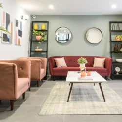 Bối cảnh phòng khách hiện đại với một bộ sofa băng màu đỏ đô làm trung tâm, kết hợp hai ghế đơn màu hồng đất. Không gian t…