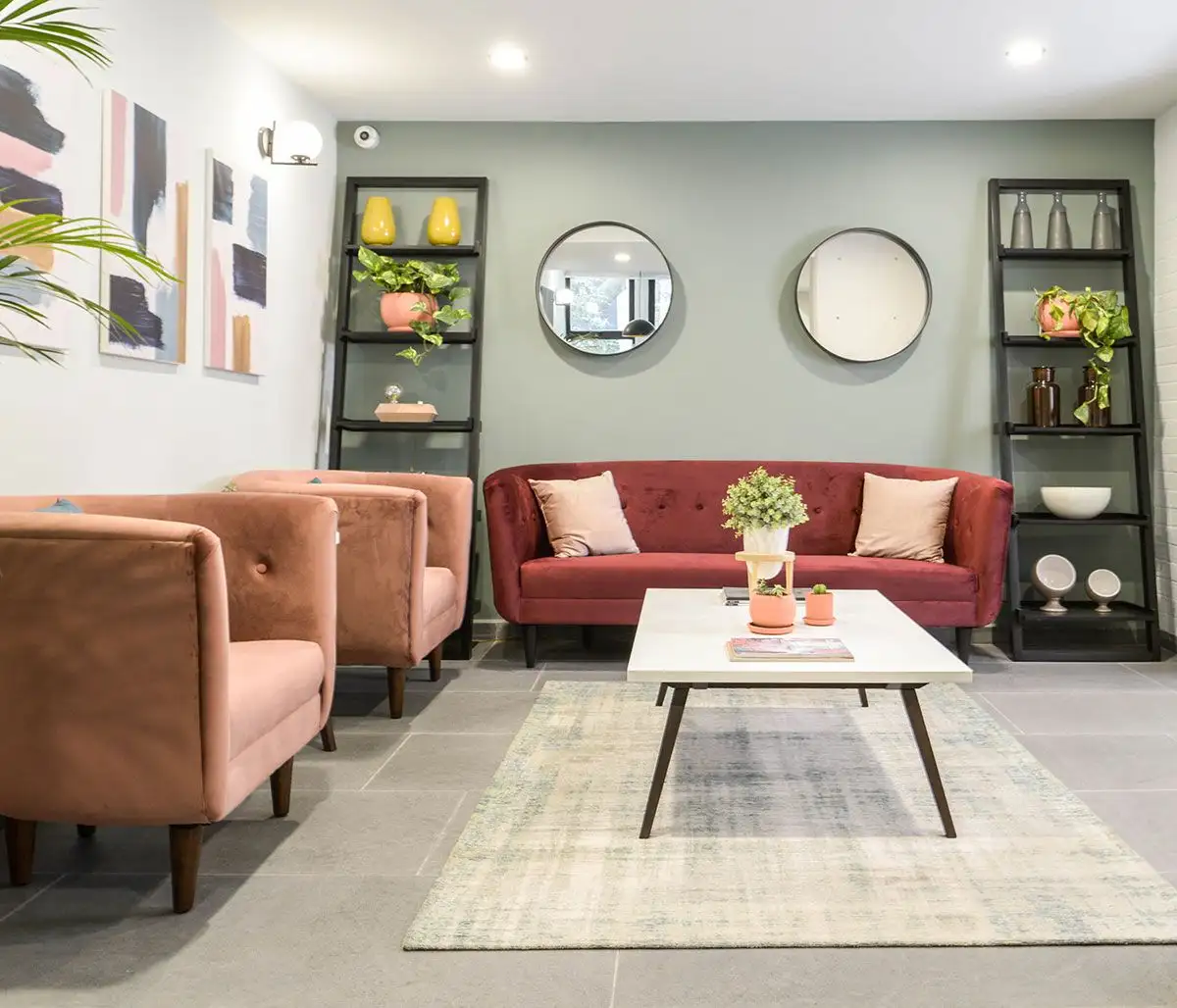 Bối cảnh phòng khách hiện đại với một bộ sofa băng màu đỏ đô làm trung tâm, kết hợp hai ghế đơn màu hồng đất. Không gian t…