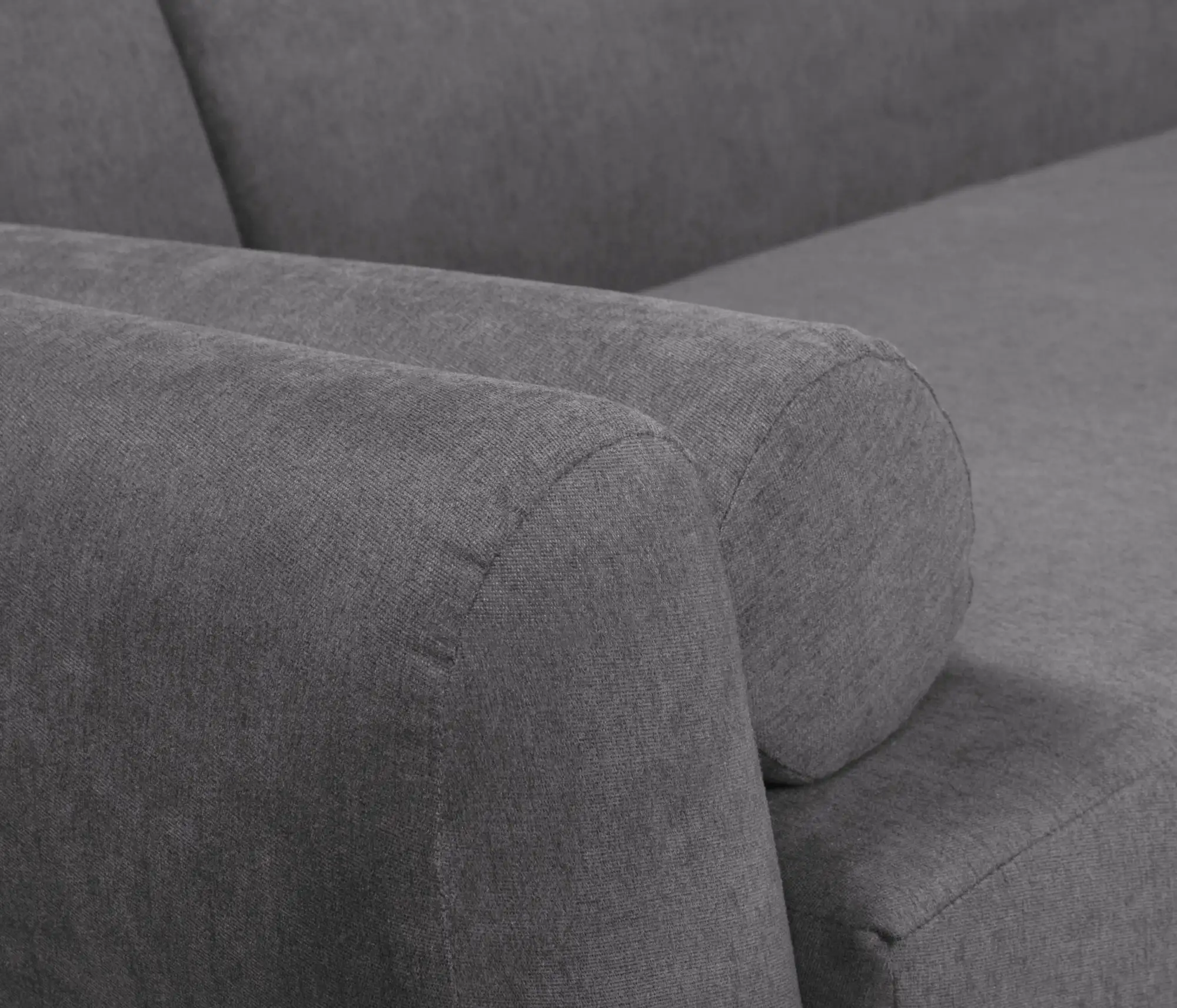 Cận cảnh chi tiết tay vịn và lưng tựa của một chiếc sofa bọc vải màu xám. Tay vịn được thiết kế bo tròn, liền mạch với lưn…