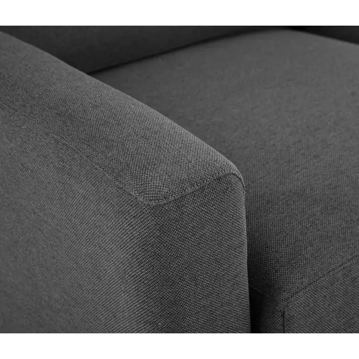 Cận cảnh góc tay vịn vuông vắn (track arms) và một phần đệm ngồi của sofa bọc vải màu xám đậm. Đường may tinh tế và chất l…
