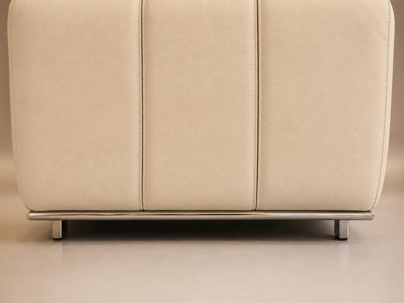 Cận cảnh phần chân và cạnh dưới của ghế đôn sofa H361-100. Ghế bọc da màu kem, với các đường may tinh tế. Phần viền chân l…