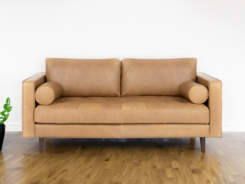 Ghế sofa Charme 001 nhìn từ góc hơi chếch, thể hiện rõ đường nét hiện đại và sự mềm mại của lớp da màu nâu vàng. Chân ghế…