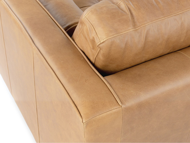 Cận cảnh chi tiết góc tay vịn của ghế sofa Charme 001, cho thấy đường chỉ may tinh tế, ẩn dưới lớp da màu nâu vàng. Gối tr…