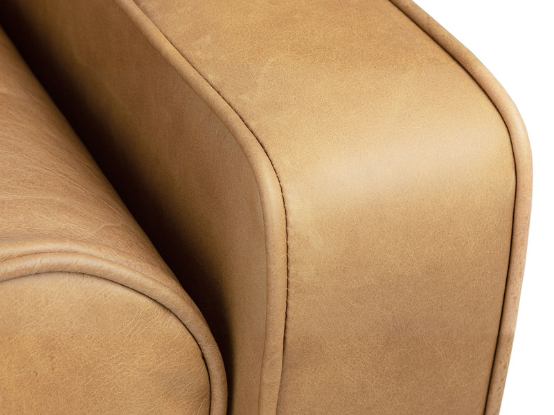 Cận cảnh đường cong mềm mại ở phần tựa lưng hoặc tay vịn của ghế sofa Charme 001. Lớp da màu nâu vàng được bọc khéo léo, t…