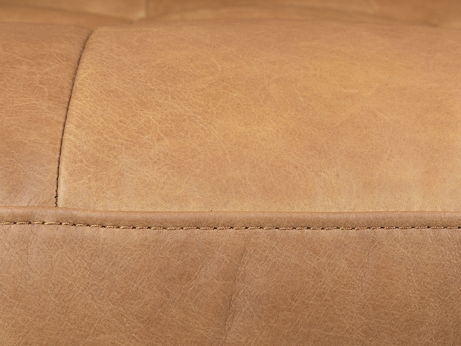 Cận cảnh đường chỉ may thủ công tinh xảo trên bề mặt da full-aniline màu nâu vàng của ghế sofa Charme 001. Từng đường kim…
