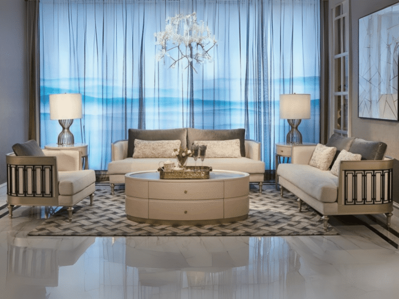 Bộ sofa phòng khách sang trọng gồm một sofa băng dài, hai sofa đơn và một bàn trà tròn lớn, được chụp chính diện trong khô…