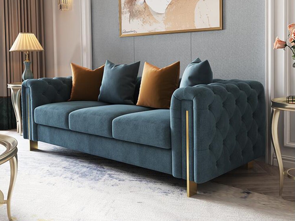 Cận cảnh ghế sofa băng ba màu xanh ngọc bích, nổi bật với đường viền kim loại mạ vàng dọc tay vịn và chân ghế. Phần hông g…