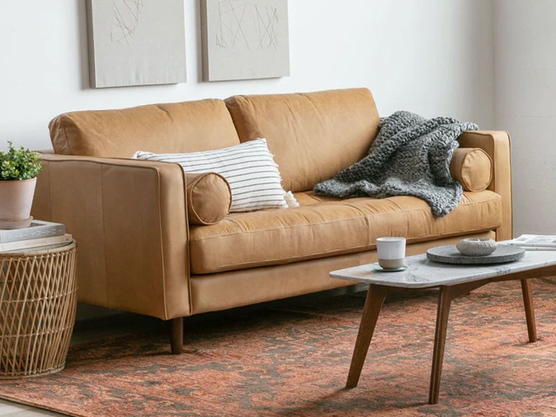 Sofa băng SF-433 bọc da công nghiệp màu nâu da bò, chụp góc nghiêng từ phải, đặt trong phòng khách hiện đại. Bối cảnh có b…