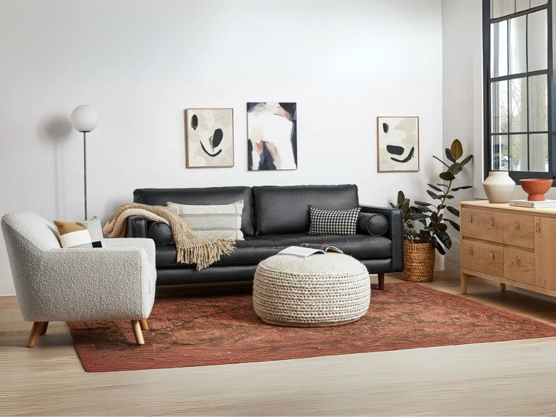 Phòng khách hiện đại với sofa băng màu đen làm trung tâm, kết hợp bàn trà tròn, thảm trải sàn họa tiết và tủ gỗ. Không gia…