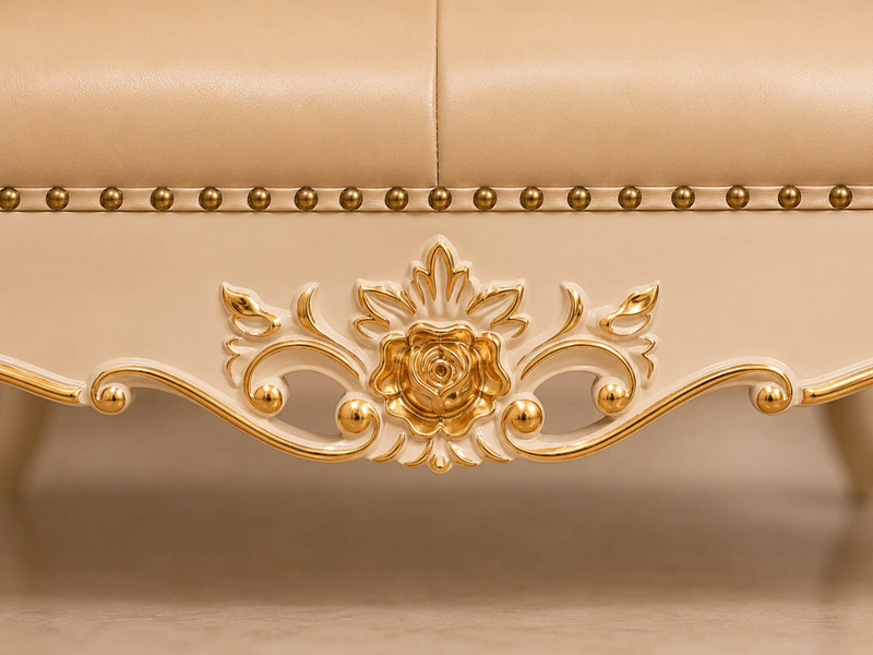 Cận cảnh phần khung gỗ sồi của ghế đôn sofa Élysée, với chi tiết chạm khắc hoa văn đối xứng hình hoa lá được mạ vàng nổi…