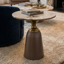 Bàn trà góc BG216 đặt cạnh ghế sofa xanh đậm trong không gian phòng khách ấm cúng với thảm lông màu kem. Bàn có mặt đá vân…