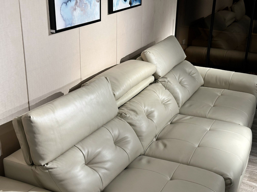 Góc chụp cận cảnh phần tựa lưng và đệm ngồi của ghế sofa chỉnh điện SF8143 màu kem nhạt. Các múi đệm phồng và nút rút được…