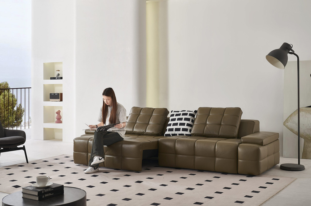 Ghế sofa chỉnh điện SF8116 màu nâu da bò, chụp ngang trong phòng khách, một người phụ nữ đang ngồi thư giãn trên phần đệm…