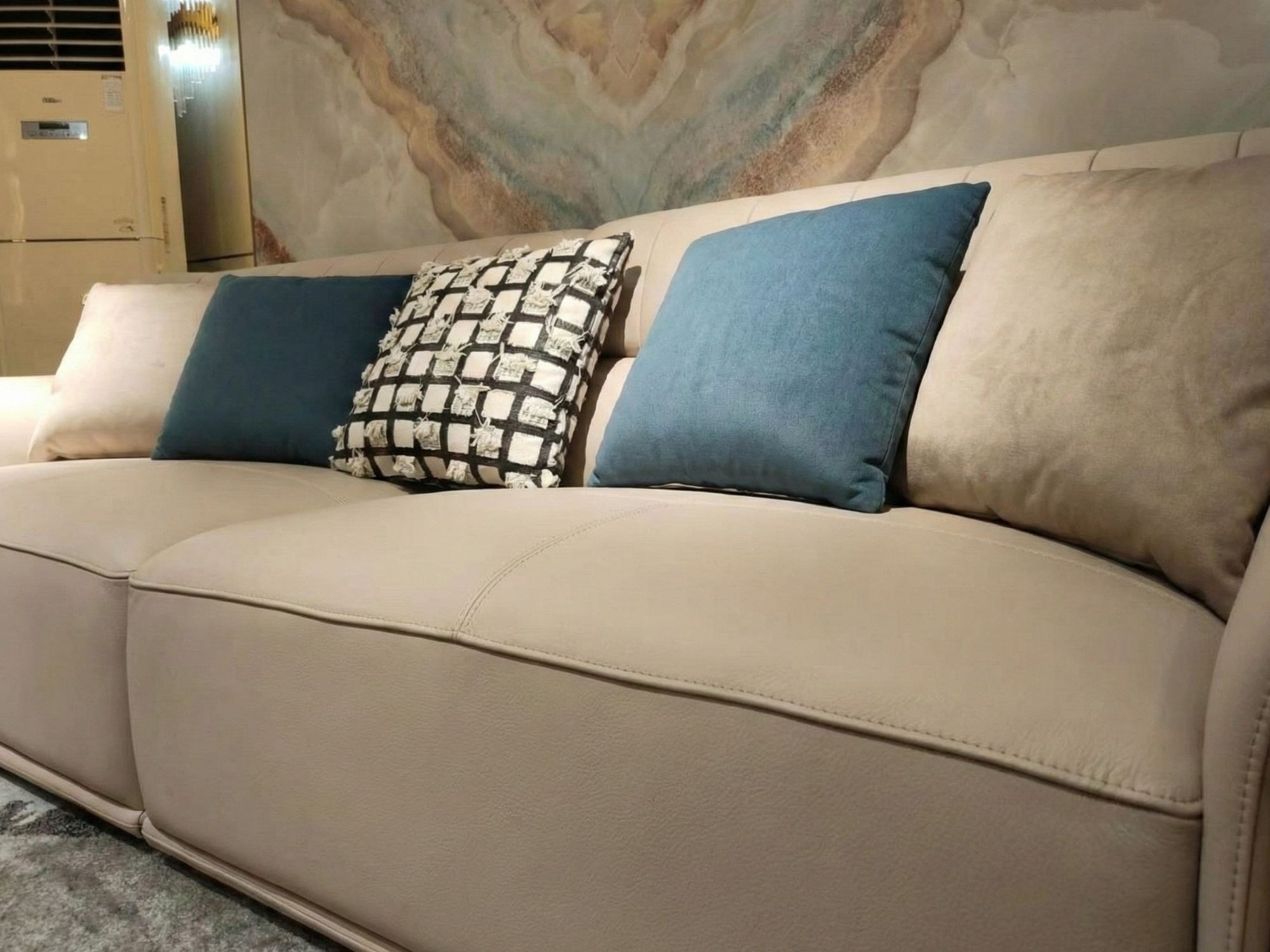 Góc chụp nghiêng cận cảnh phần đệm ngồi và tựa lưng của sofa SBQ929-4. Bề mặt da bò tự nhiên màu be nhạt căng mịn, đường c…