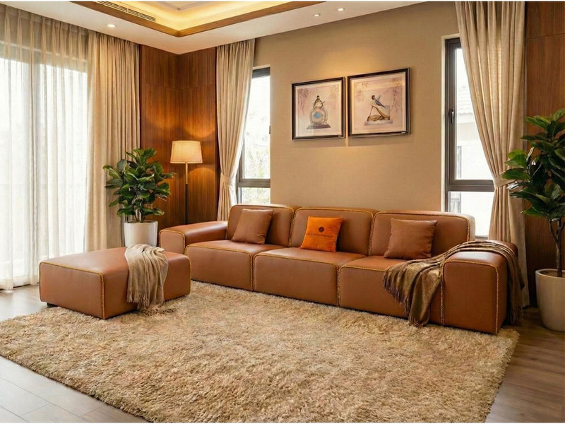 Toàn cảnh bộ sofa băng SFA38-32 và đôn, bọc da bò tự nhiên màu nâu ấm áp, nổi bật trên nền thảm lông màu be. Bố cục cân đố…