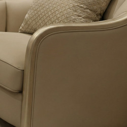 Cận cảnh tay vịn của ghế sofa băng, cho thấy đường cong mềm mại và lớp bọc da sinh thái màu be nhạt. Chi tiết đường viền đ…