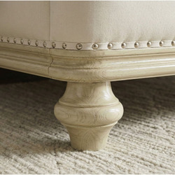 Chi tiết chân giường GI2803-18 hình trụ tròn tiện hoa văn, sơn màu vàng nhạt, đặt trên thảm lông màu trắng. Phần viền khun…