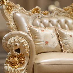 Góc nhìn cận cảnh phần tựa lưng và gối tựa của ghế sofa, cho thấy rõ chất liệu da bò màu kem và các nút rút. Phía trên là…