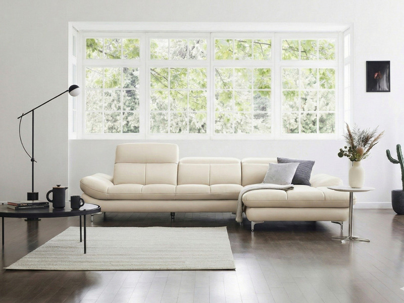 Sofa ASCEND kiểu dáng góc phải, màu kem ngả, được bố trí trong không gian phòng khách hiện đại với thảm lông màu xám và bà…