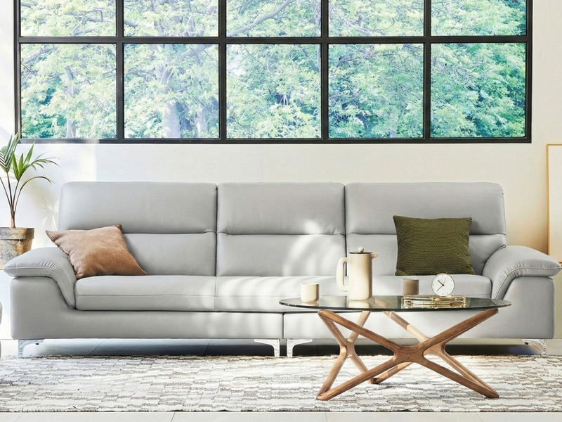 Sofa băng 3 chỗ CALMHAVEN màu xám nhạt, kiểu dáng hiện đại tối giản, đặt trong phòng khách có cửa sổ lớn. Sofa có đệm ngồi…