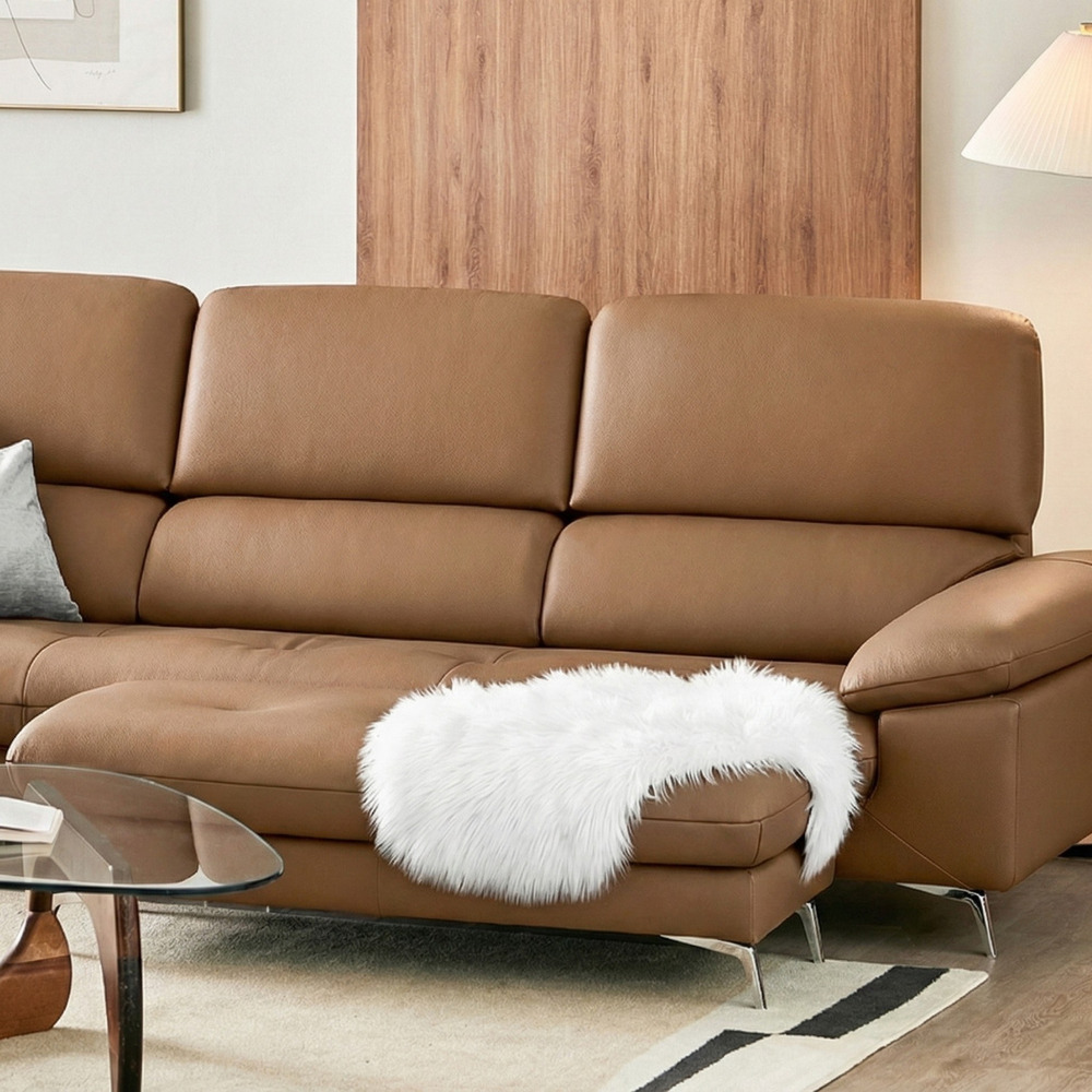 Góc cận cảnh sofa Ravell chữ L màu nâu latte, tập trung vào phần tay vịn kiểu daybed rộng rãi và mềm mại, có gối lông trắn…