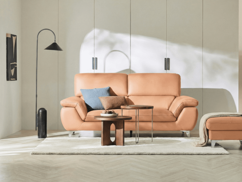 Sofa băng 2 chỗ HEARTWARMING màu cam đất, đặt trong phòng khách hiện đại với tường trắng và sàn gỗ. Góc chụp chính diện, t…