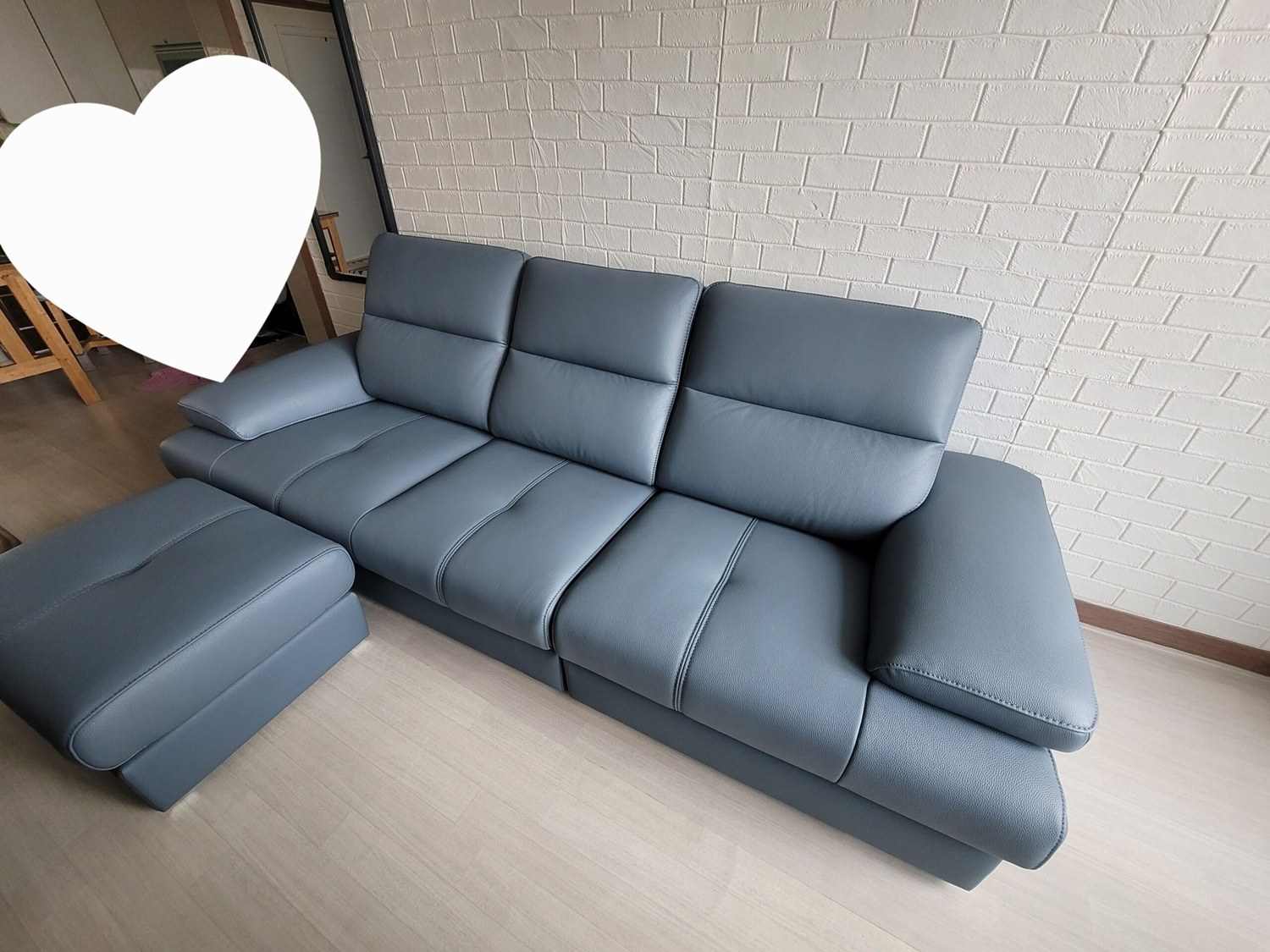 Góc chụp chéo cận cảnh sofa LULLABY màu xanh xám, làm nổi bật bề mặt da mịn màng và các đường may tinh xảo trên đệm. Sofa…